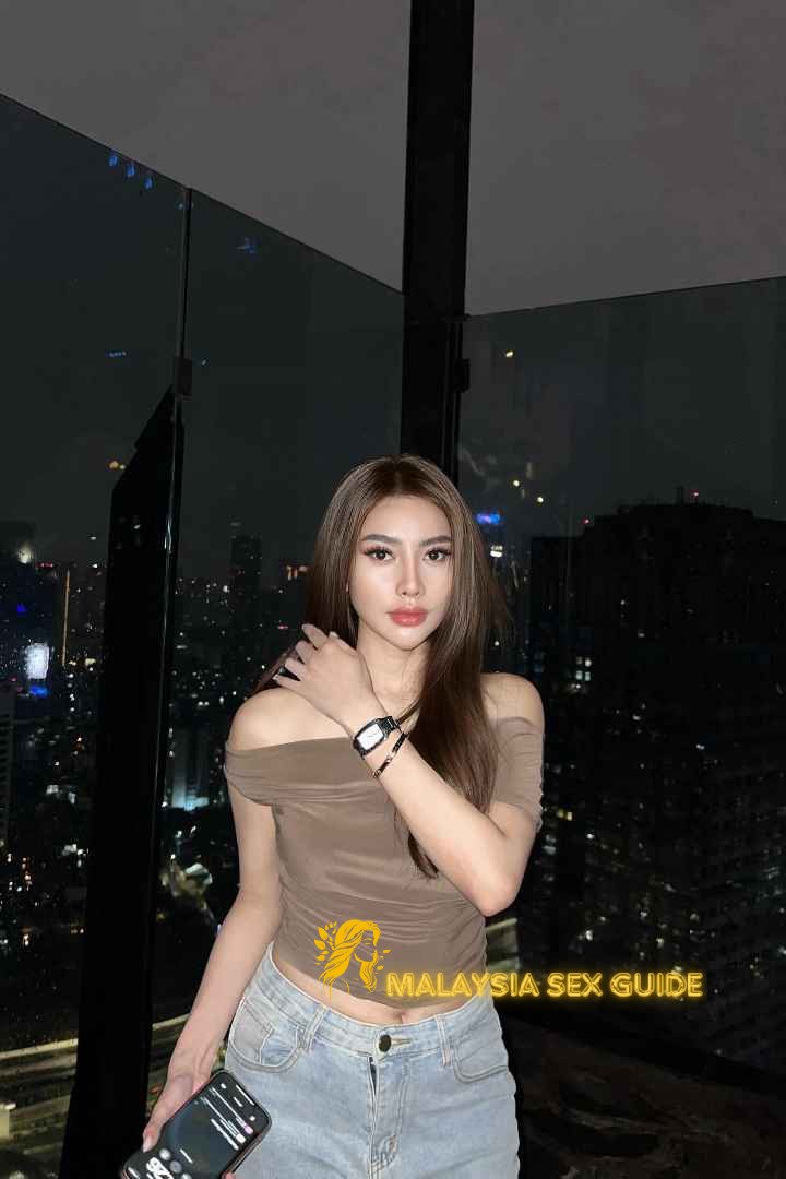 Attractive Malay woman in a brown top and jeans, enjoying a city view.