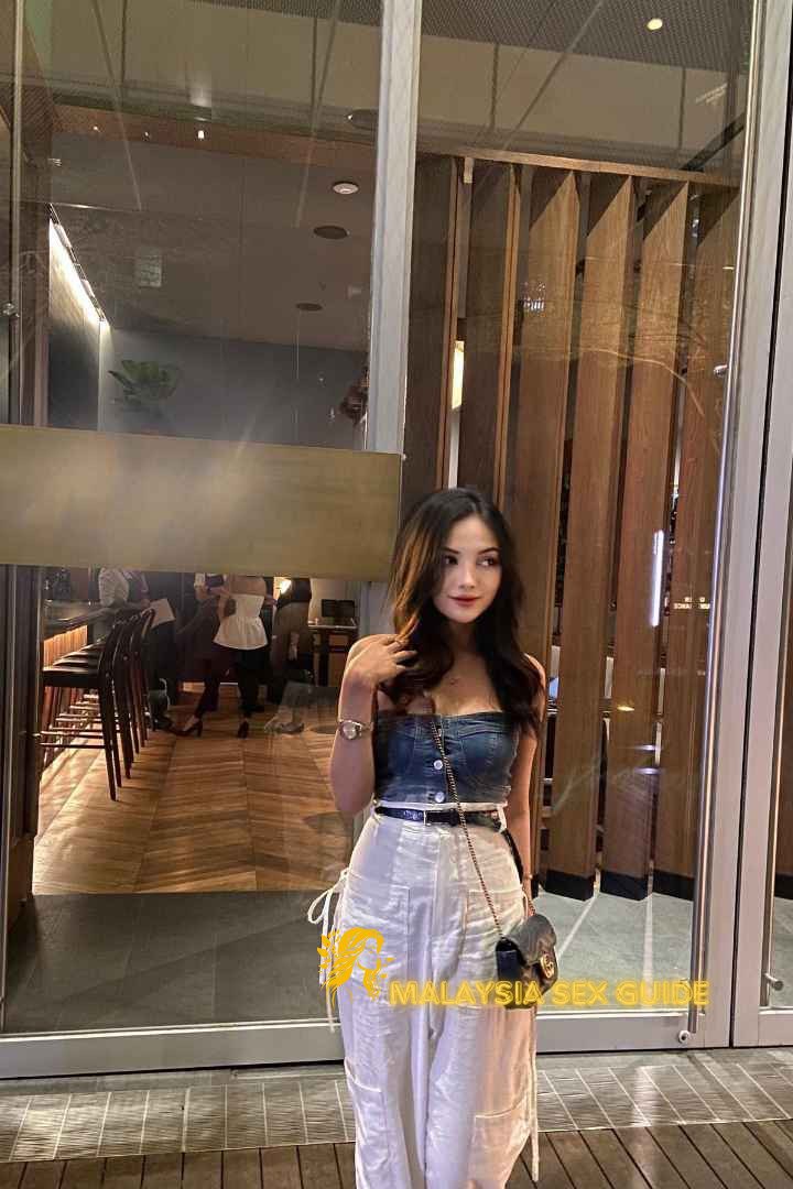 Attractive young woman in denim top and white pants in KL.