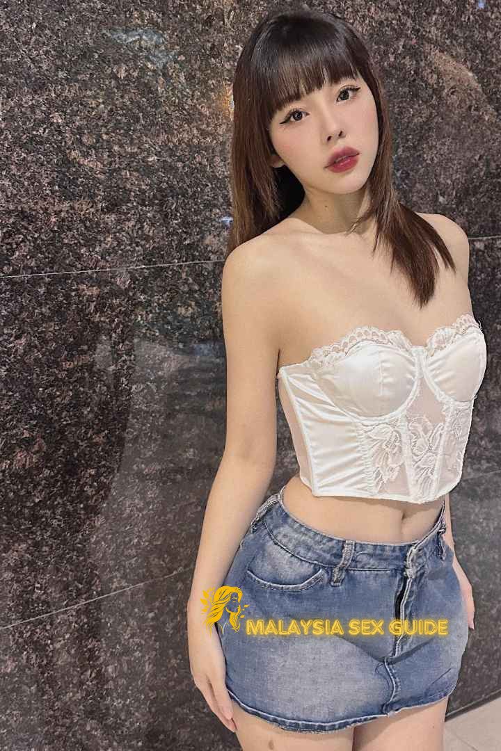 Attractive young woman in white corset and denim skirt. Malaysia sex guide.