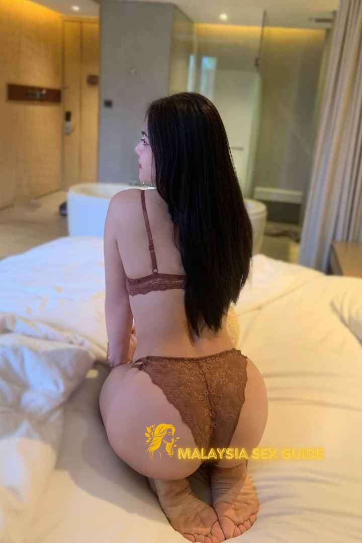 Woman in brown lingerie sitting on a bed