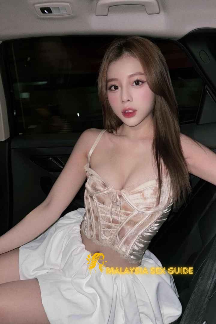 Attractive young woman in a beige corset and white skirt. Malaysia sex guide.