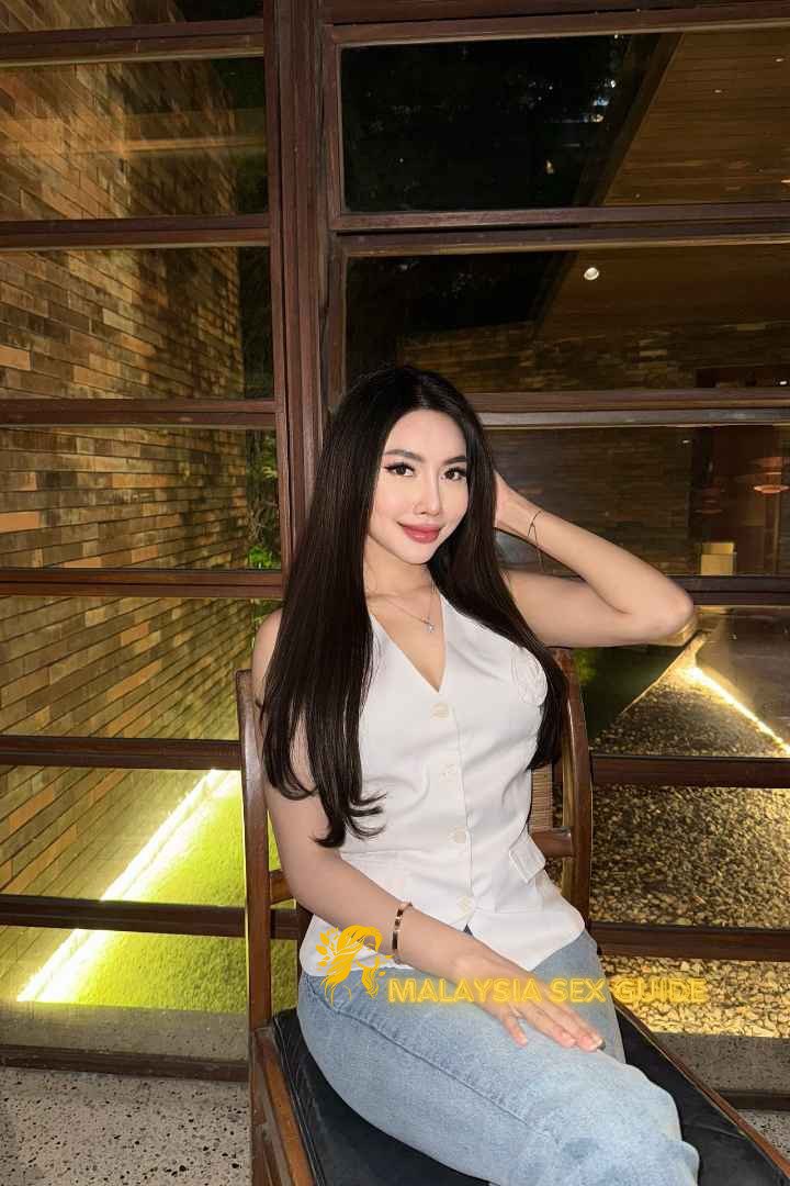 Attractive Malay woman in a white vest and jeans.