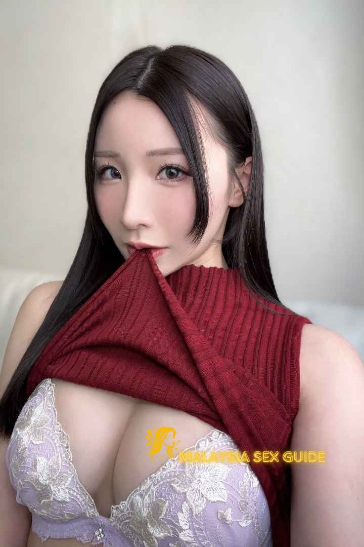 Attractive young woman partially revealing her bra underneath a red sweater.
