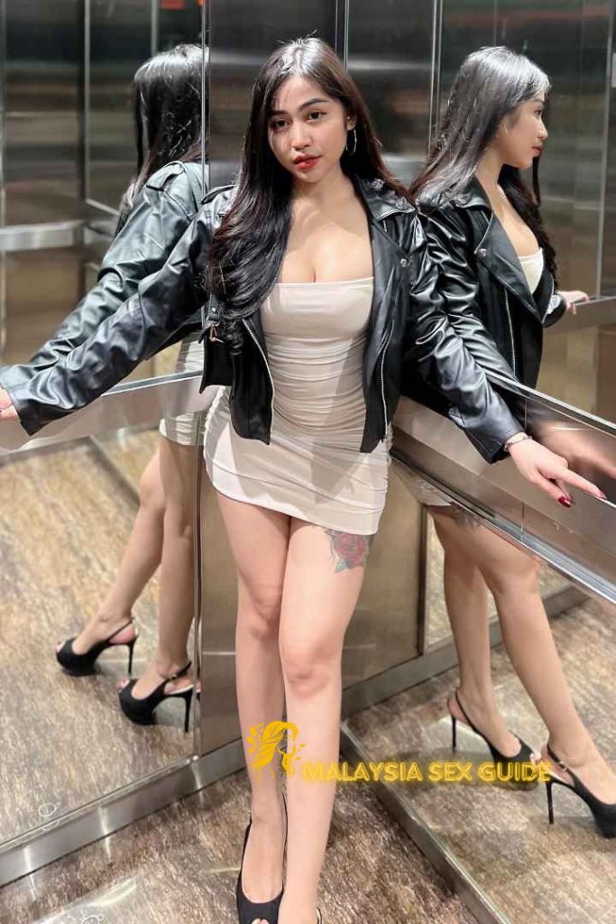 Woman in leather jacket and dress in a reflective elevator.