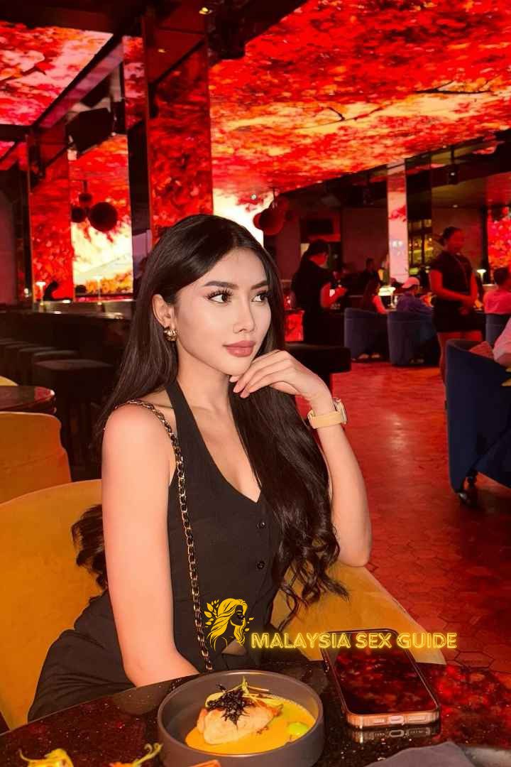 Attractive Malay woman in a black dress at a bar.