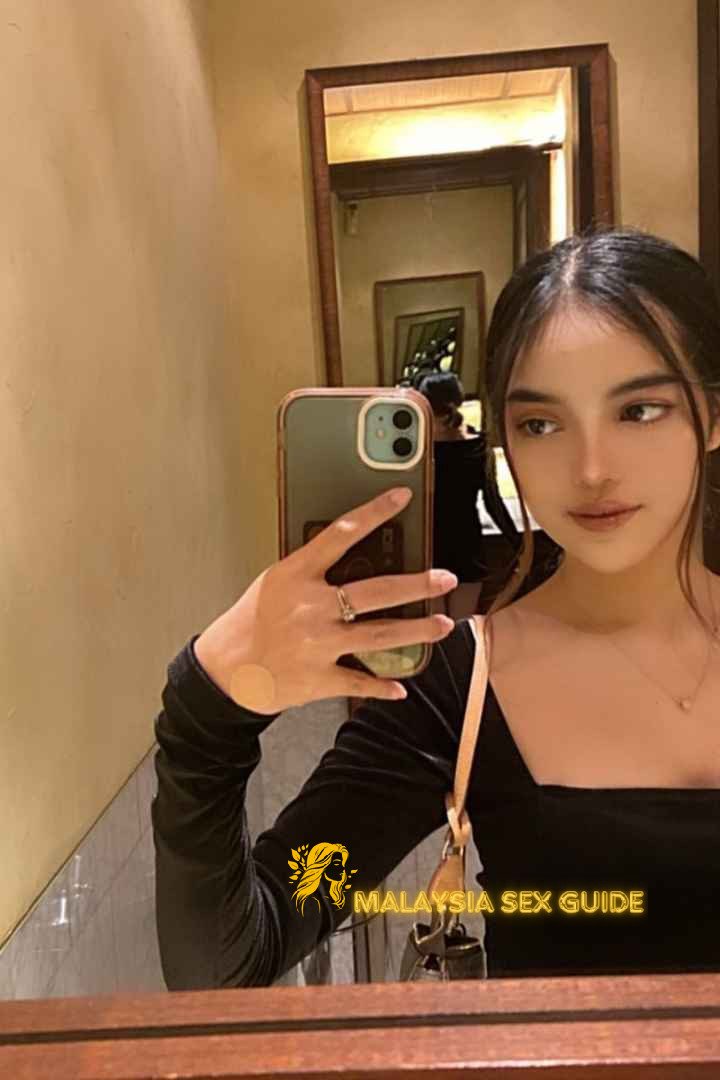 Young woman taking a selfie in a restroom mirror.
