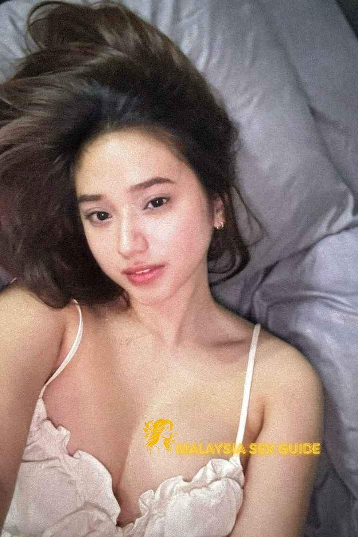 Attractive young woman in a white top lying on a bed.
