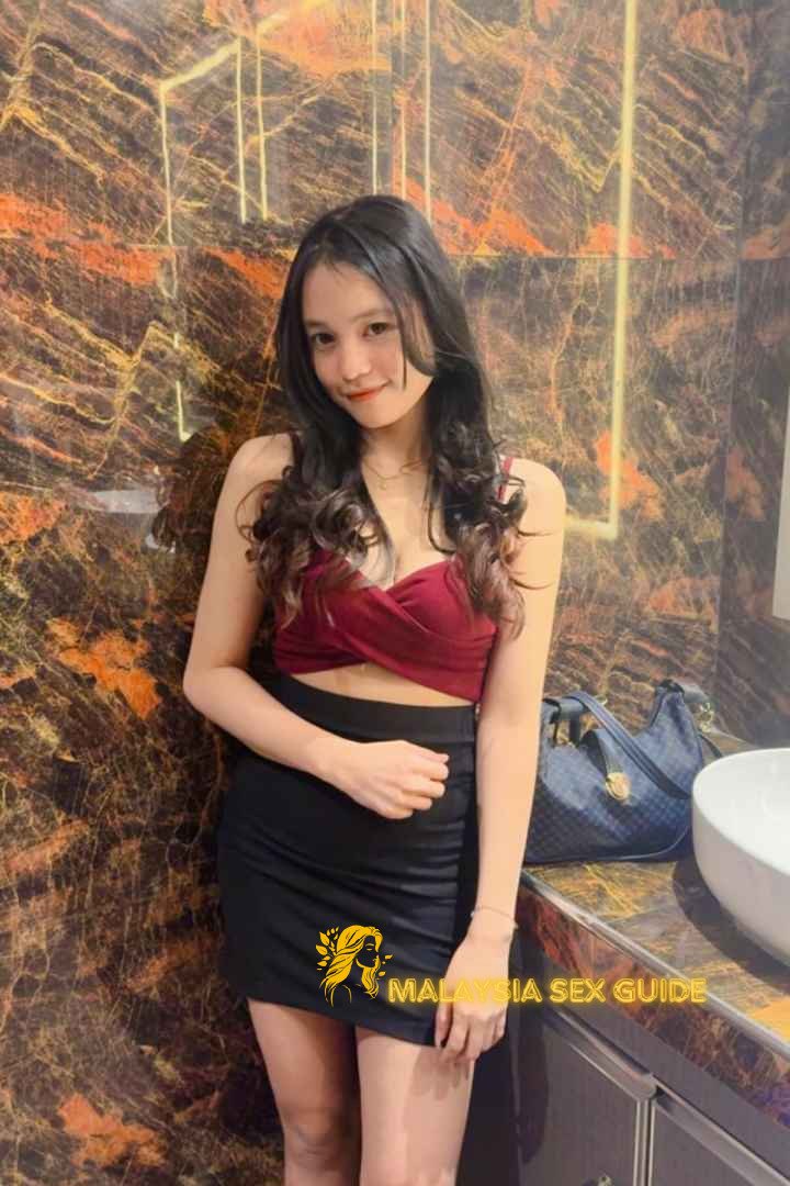 Attractive young woman in a red top and black skirt. Kuala Lumpur escort.