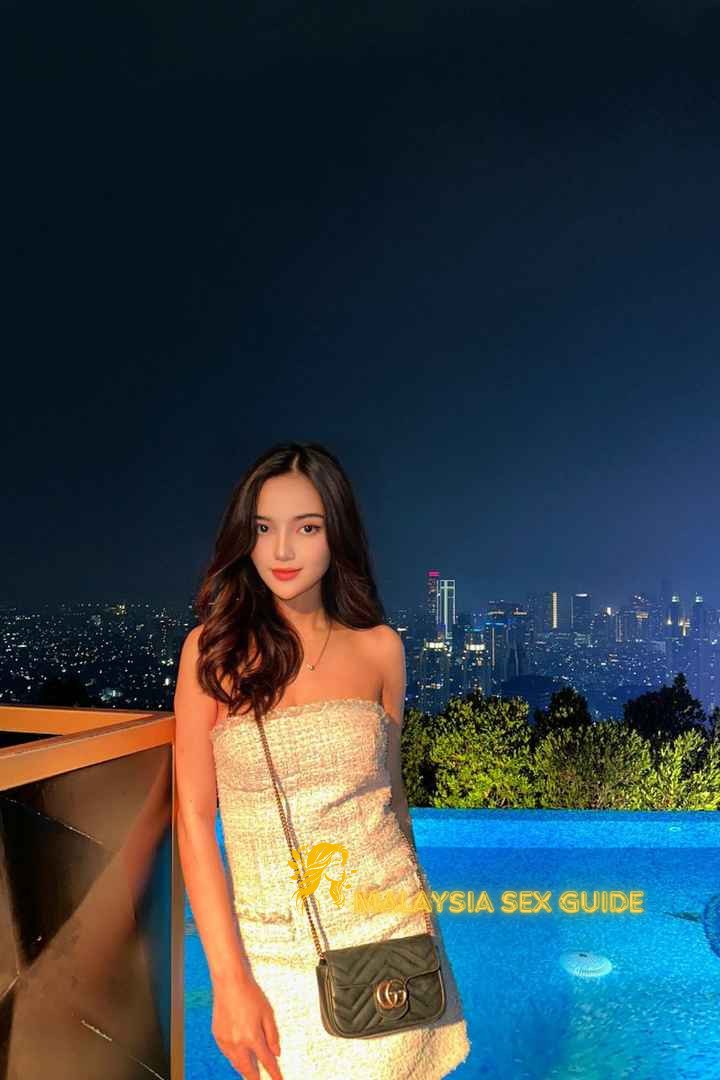 Attractive young woman in KL, wearing a stylish dress and handbag.