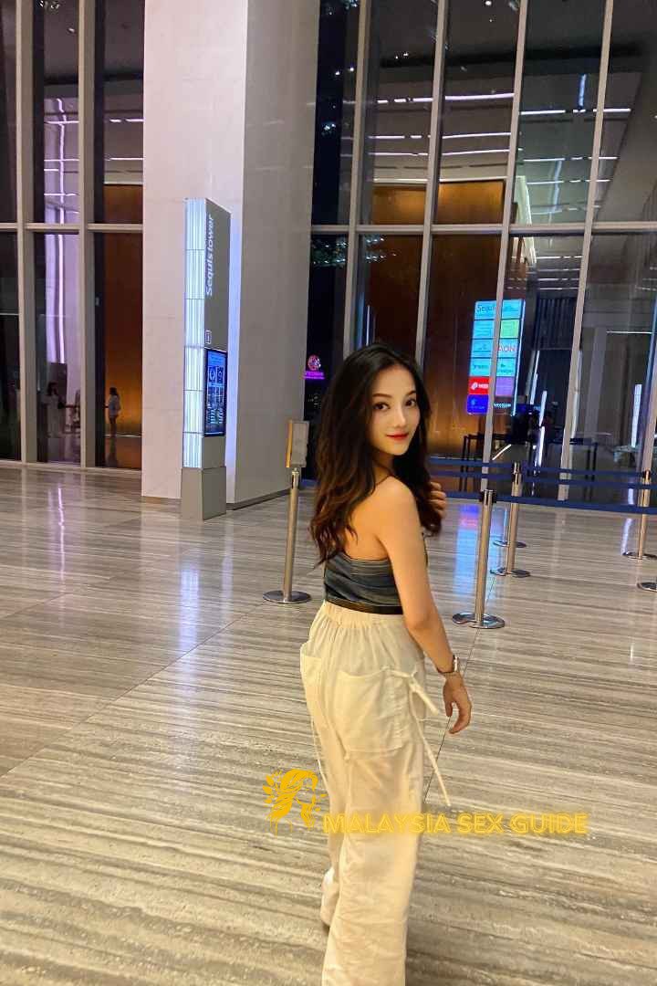 Young woman in stylish pants standing in a modern building lobby.